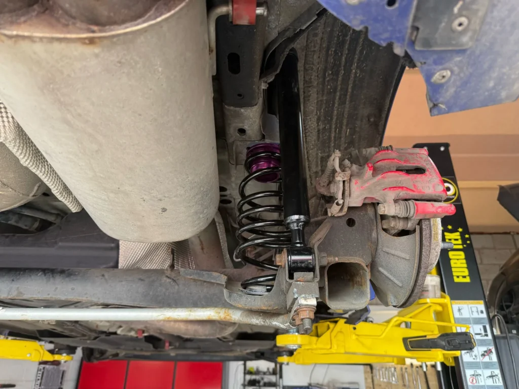 Close-up of rear suspension and brake caliper during coilover and polybush installation on a VW Golf